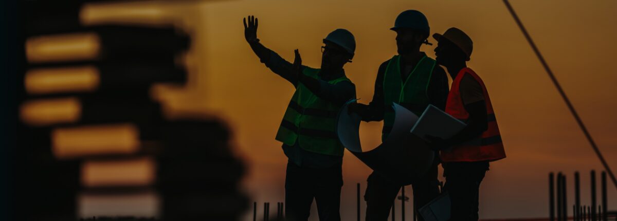 Burkes Mechanical crew reviewing plans on a jobsite at dusk