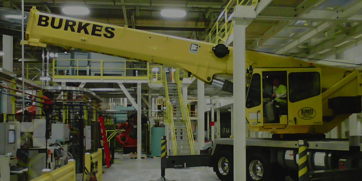 Burkes 60-ton crane operating inside an industrial facility, performing precision equipment setting in a controlled environment.