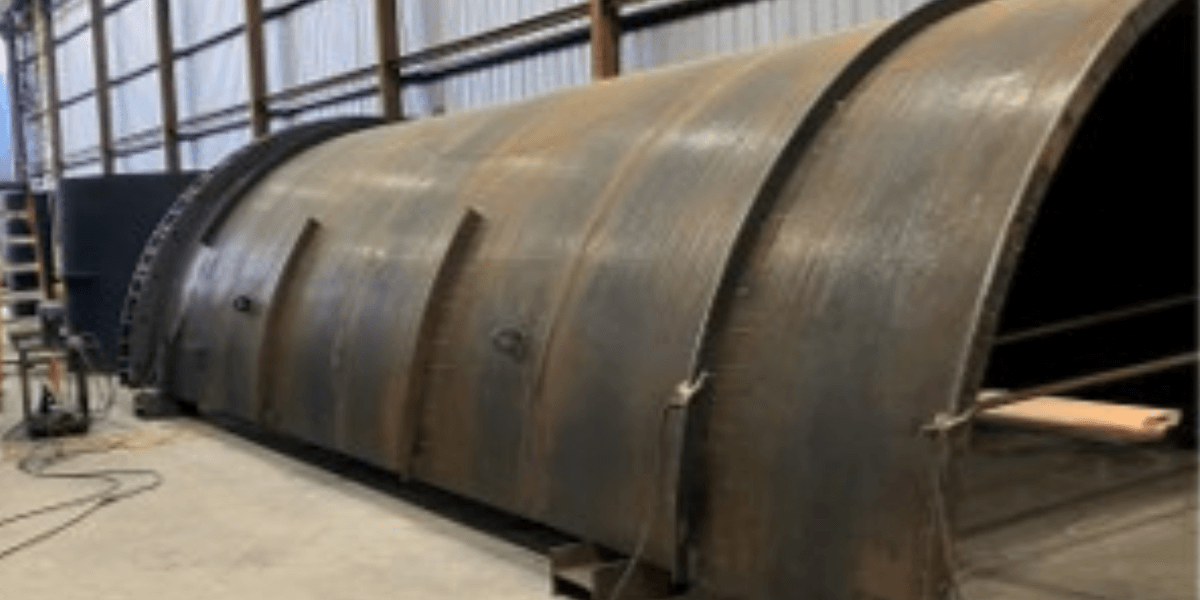 Large steel vessel shell under fabrication inside Burkes’ shop, showing welded seams and heavy-duty structural reinforcement.