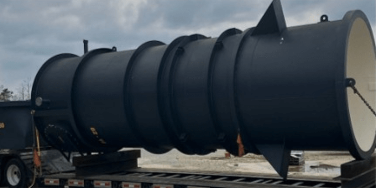 Large black industrial pressure vessel loaded on a flatbed trailer, fabricated for heavy-duty processing and transport.