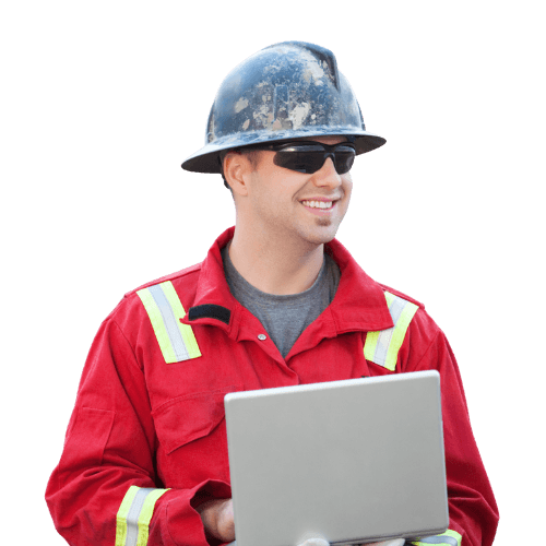 Industrial worker in red protective uniform and hard hat, wearing safety glasses and smiling while using a laptop. 