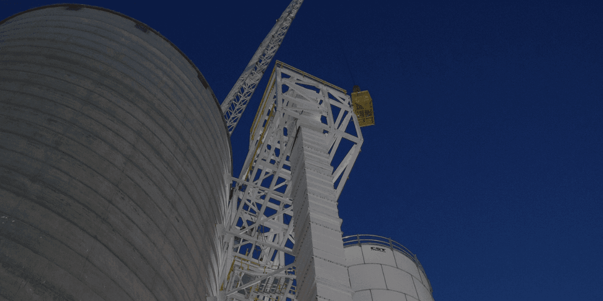 Burkes Mechanical industrial crane lifting and setting large storage tank at a manufacturing facility, supporting heavy equipment installation and capital projects across the Southeast
