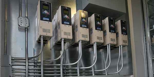 Burkes Mechanical electricians installing a row of Yaskawa variable frequency drives with conduit wiring at an industrial facility in the Southeast US, showcasing certified industrial electrical services including controls installation and automation system upgrades