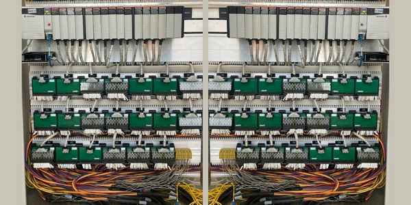 Burkes Mechanical DCS and PLC installation showing dual Allen Bradley rack mounted control system panels with green I/O modules, terminal blocks, and organized multi-color wiring bundles in an industrial control enclosure