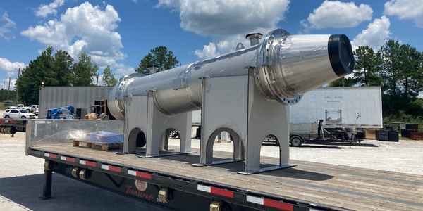 Burkes Mechanical fabricated polished stainless steel pressure vessel mounted on structural saddle supports loaded on a flatbed trailer for delivery to an industrial client in the Southeast US, highlighting ASME certified vessel fabrication capabilities