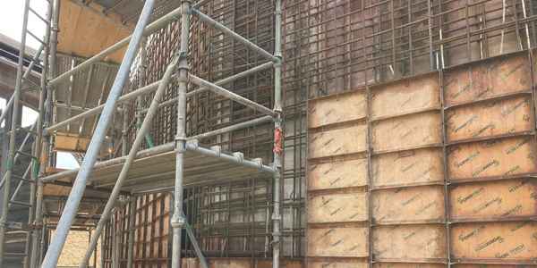 Burkes Civil Services crew installing multi-level scaffolding alongside reinforced rebar walls and concrete formwork panels at a large industrial construction project in the Southeast US, demonstrating full-scope civil construction expertise