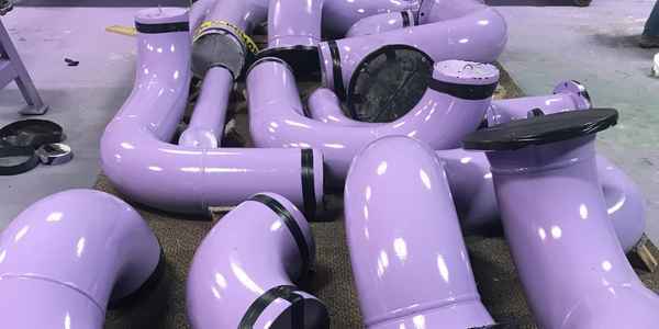 Burkes Mechanical fabricated and coated industrial pipe spools and elbows staged in the fabrication shop, demonstrating precision pipe fabrication and protective coating services for corrosive industrial environments in the Southeast US